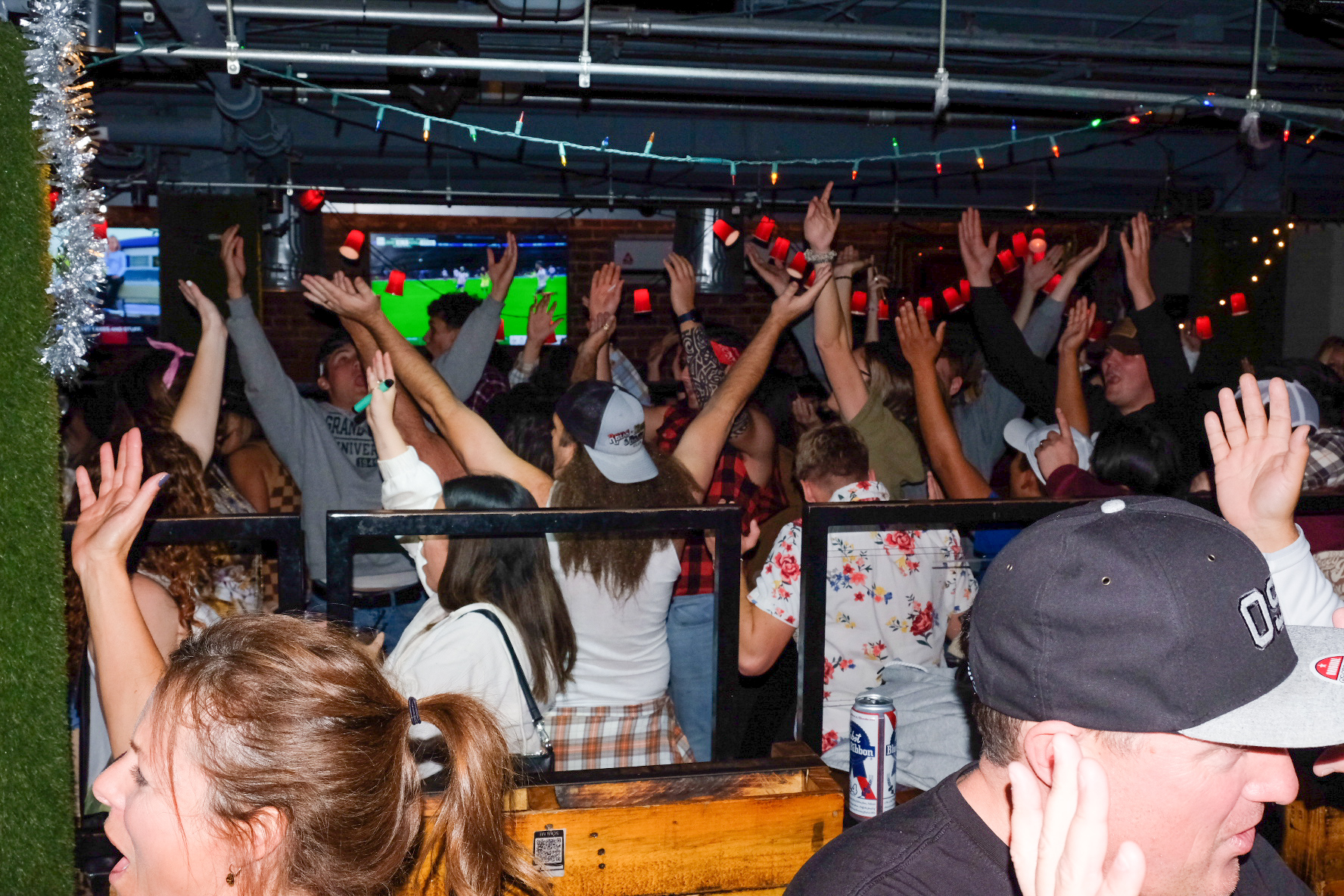 Packed holiday crowd cheering under tinsel garland during a full venue buyout at Trailer Park After Dark in the Gaslamp Quarter