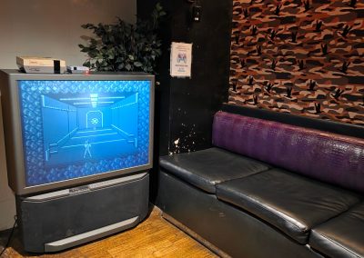 Retro rear-projection TV facing a leather booth in the trailer park lounge