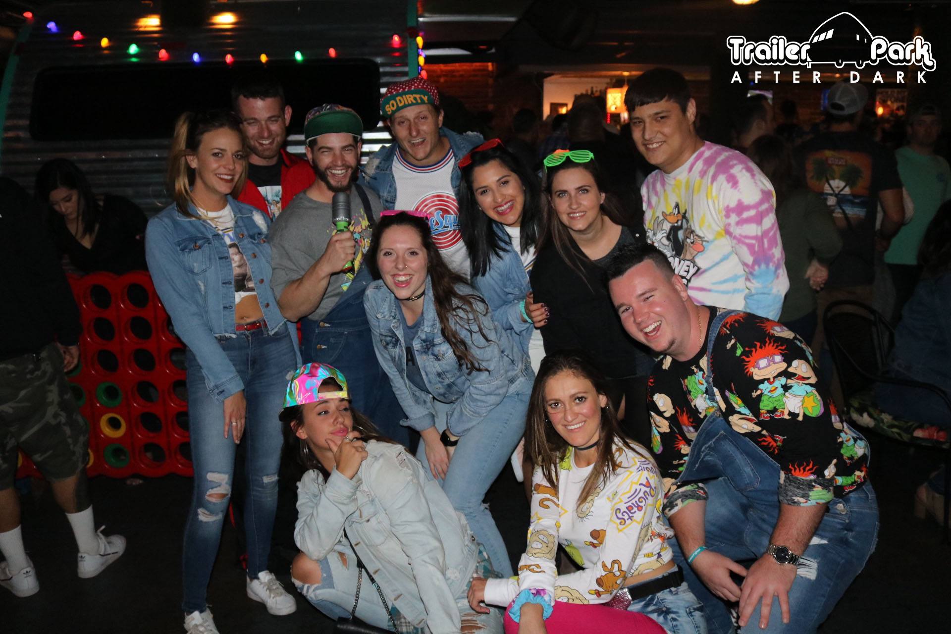 Holiday party group posing beside the giant Connect Four board at Trailer Park After Dark