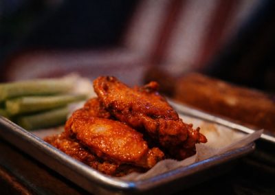 Saucy chicken wings on a metal tray with green beans