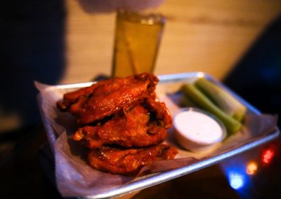 Buffalo wings in a basket with ranch dressing and celery sticks