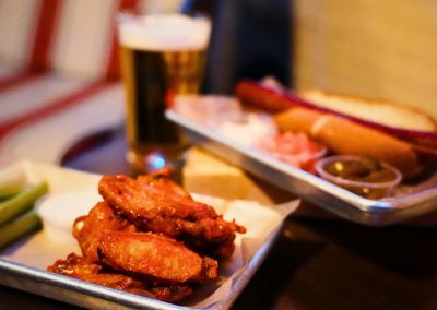 Fried chicken wings and green beans with a beer and hot dog behind