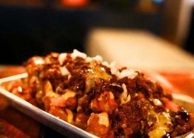 Tater tots loaded with chili, melted cheese and diced onions on a tray