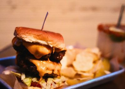 Double cheeseburger with melted cheese served with potato chips on a blue tray
