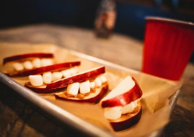 Apple slices with marshmallow teeth lined up on a paper-lined tray